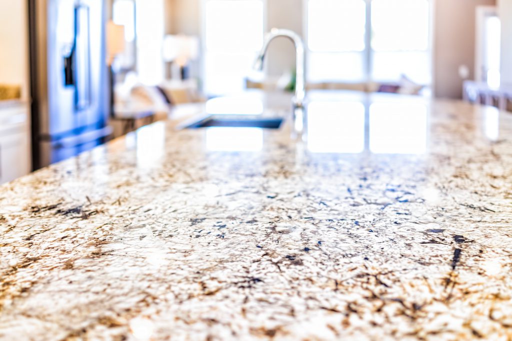 closeup on kitchen island countertop with silver faucet and sink